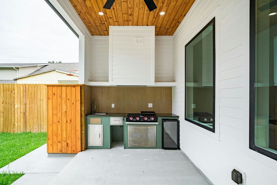 Modern outdoor kitchen with white cabinets and a gas grill.