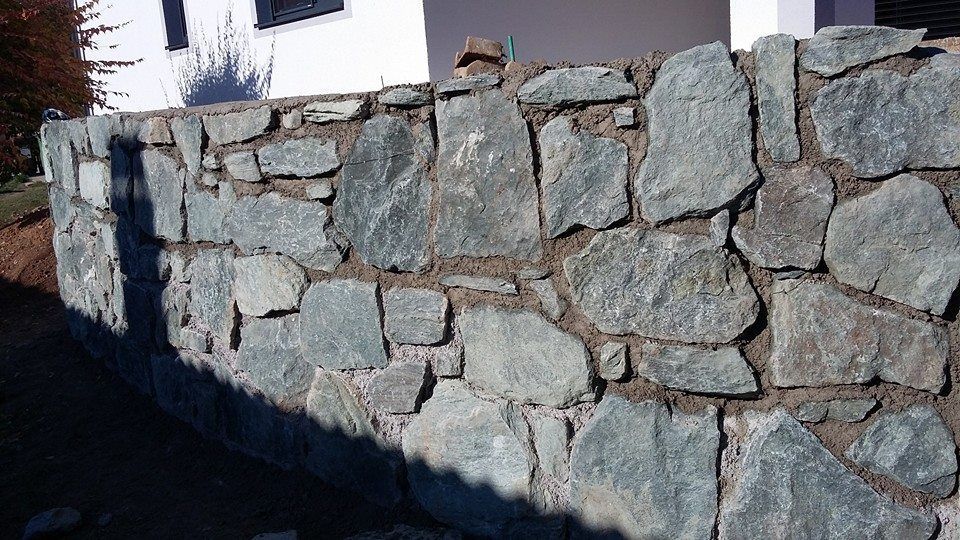 Vor einem Haus wird eine Steinmauer gebaut.