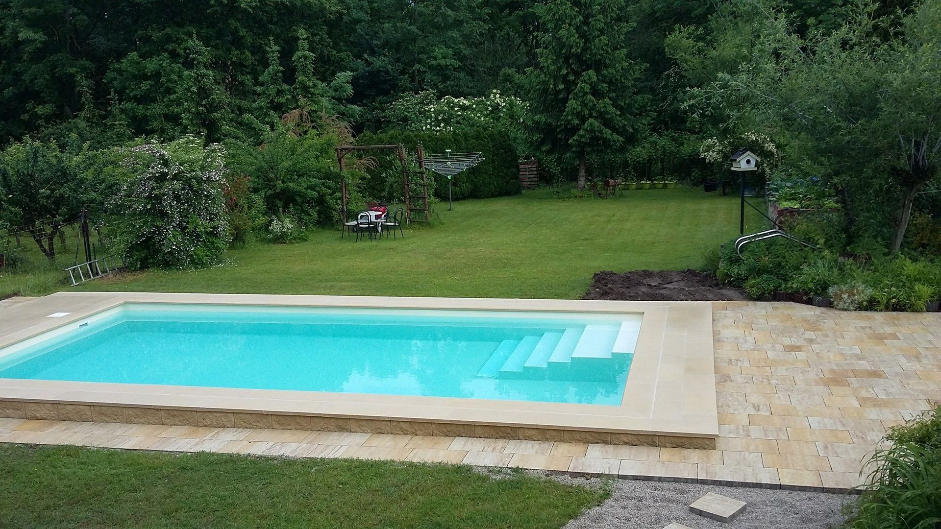 Ein großer Swimmingpool inmitten eines üppig grünen Gartens.