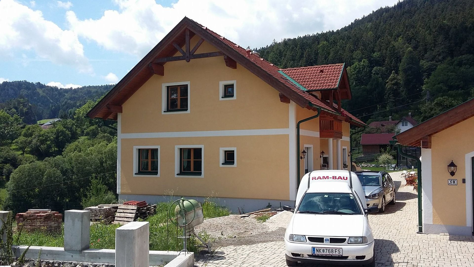 Ein weißes Auto parkt vor einem Haus mit rotem Dach
