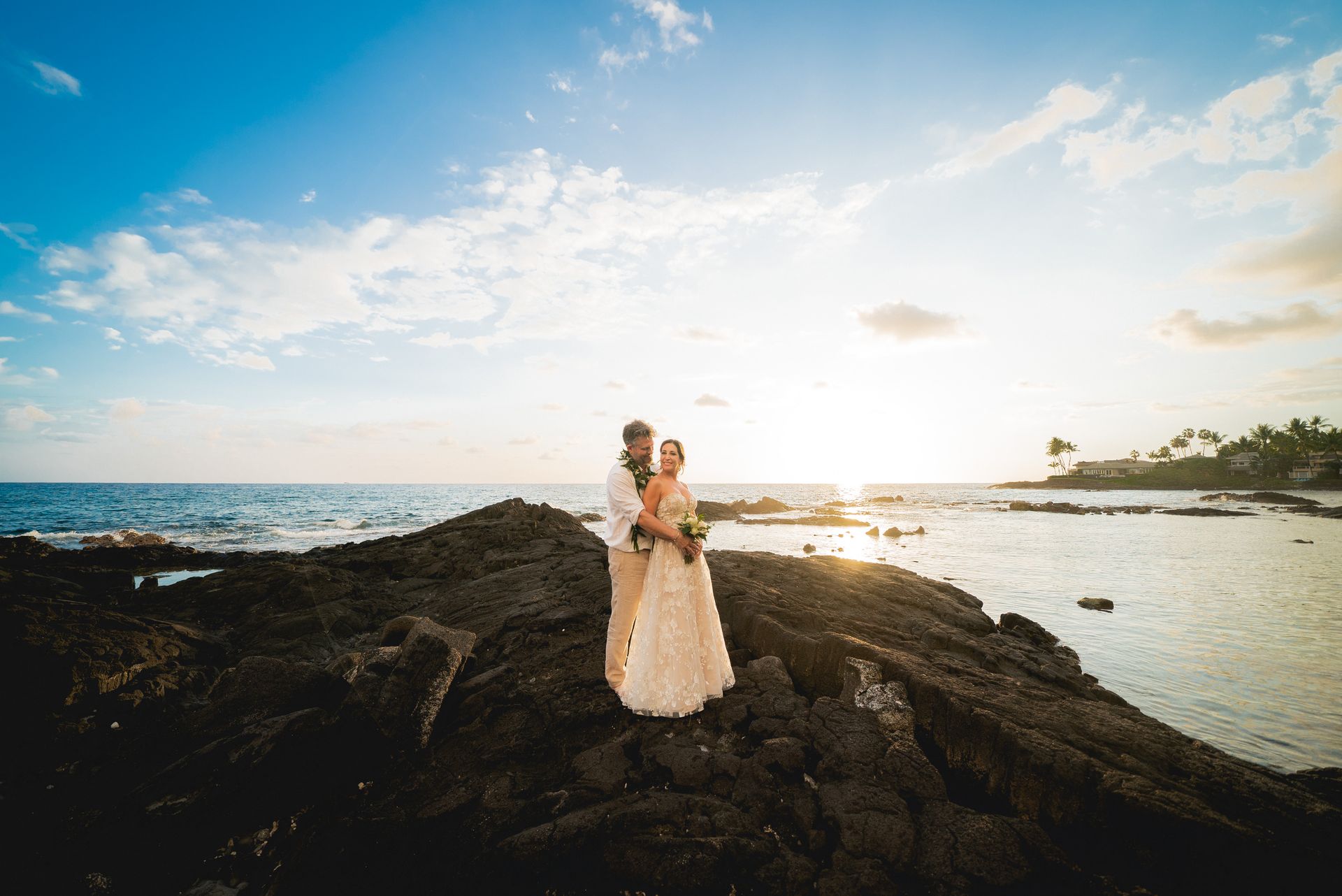 Silhouetted couple kissing on beach at sunset, vibrant orange and blue sky over water.
