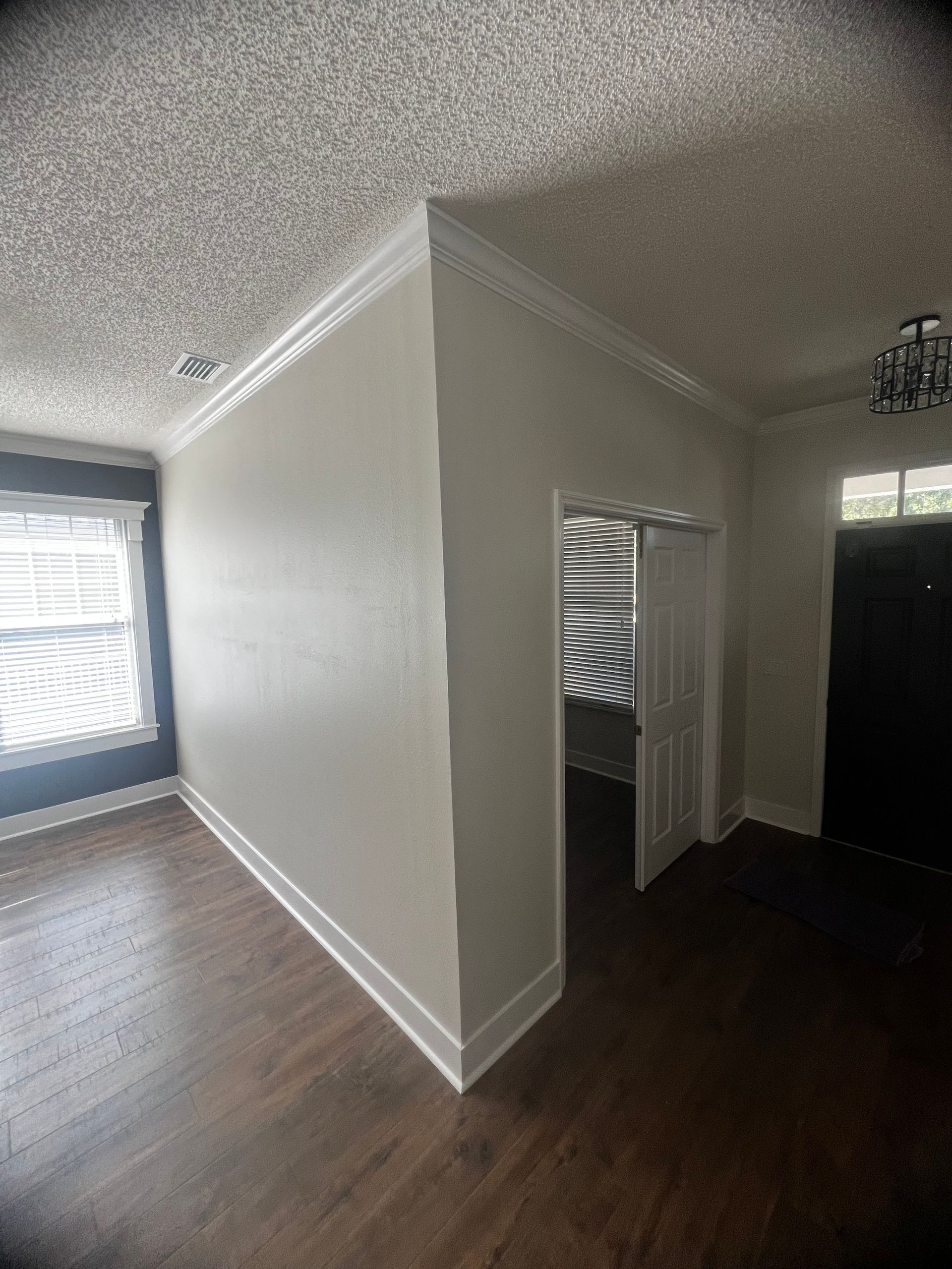 An empty living room with hardwood floors and white walls.