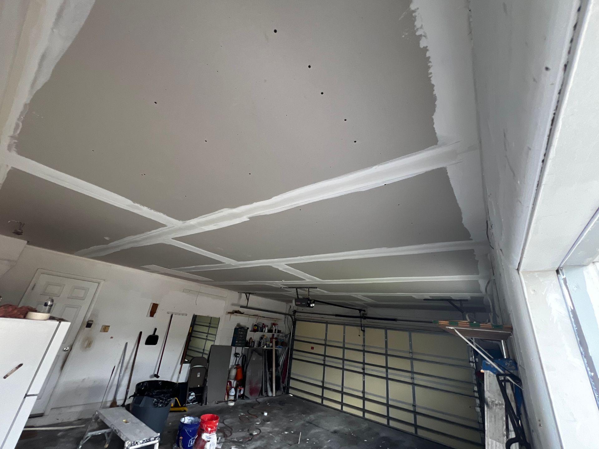 A garage with a garage door and a ceiling that is being remodeled.
