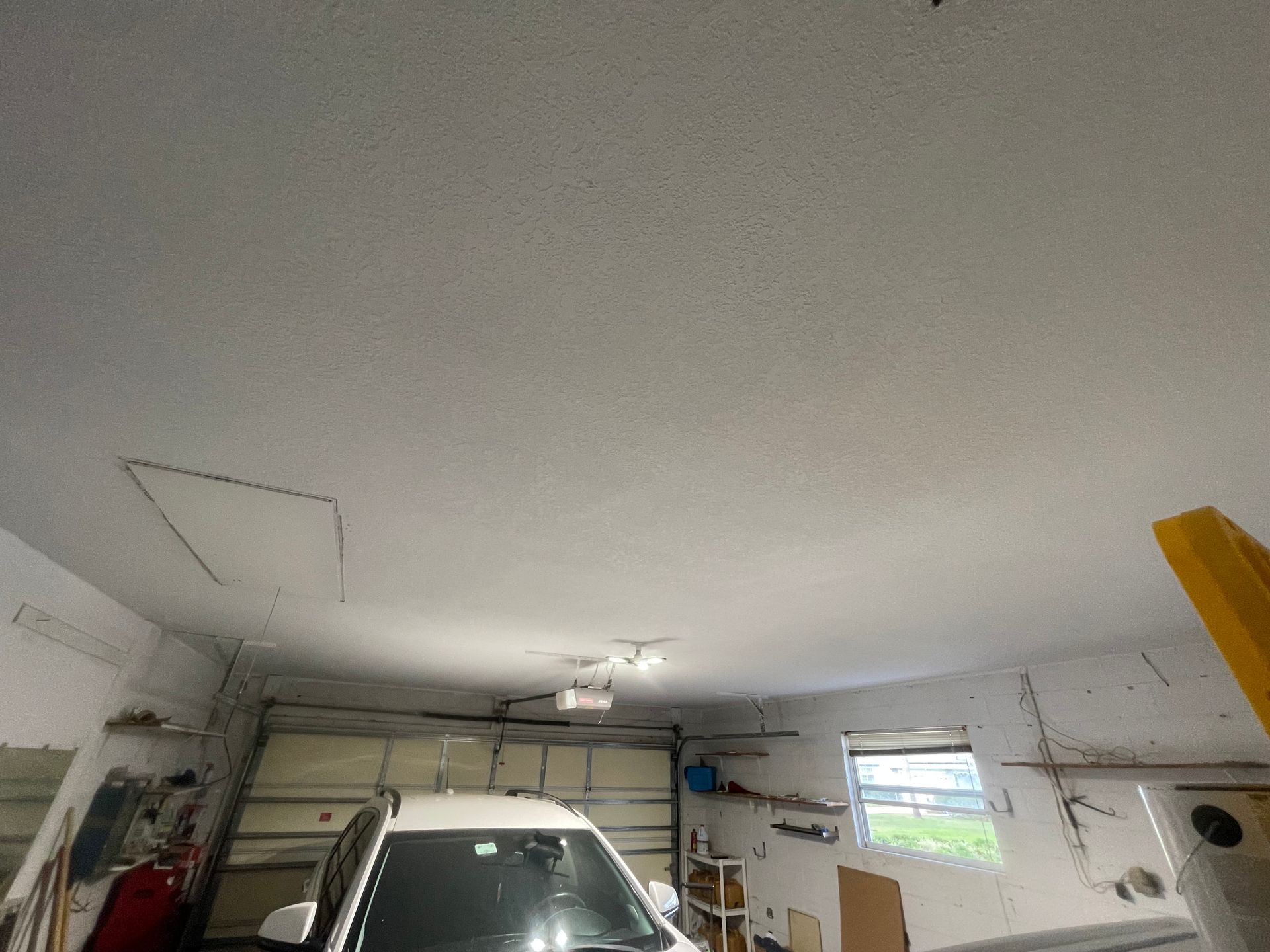 A car is parked in a garage with a garage door open.