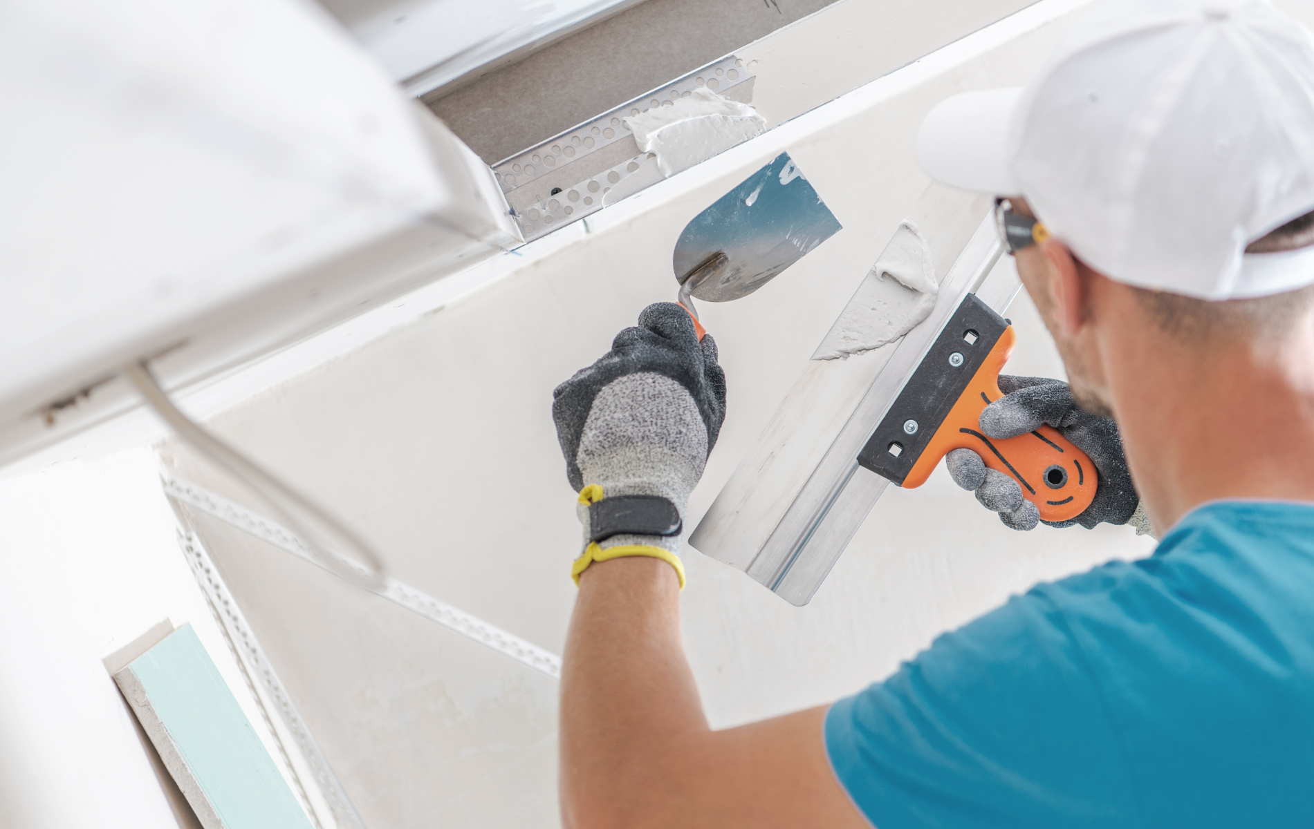 A man is plastering a ceiling with a spatula.