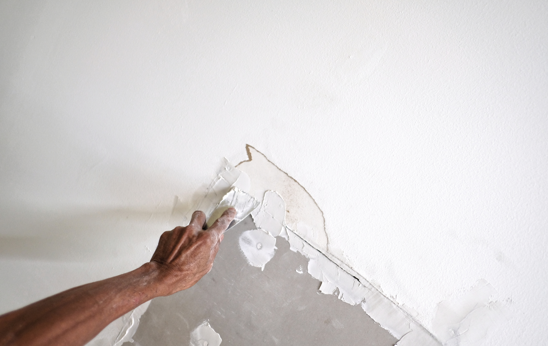A person is plastering a wall with a trowel.
