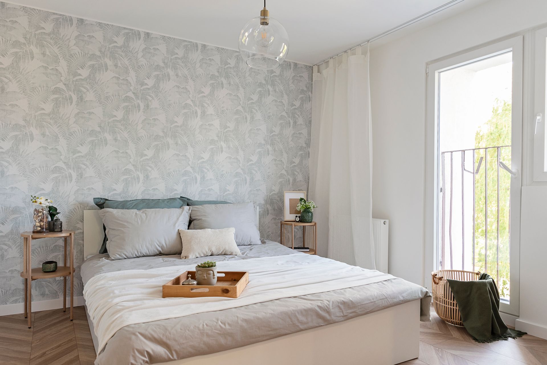 Bright bedroom with a beige bed, gray textured wall, bedside tables, and a balcony door with sheer curtains