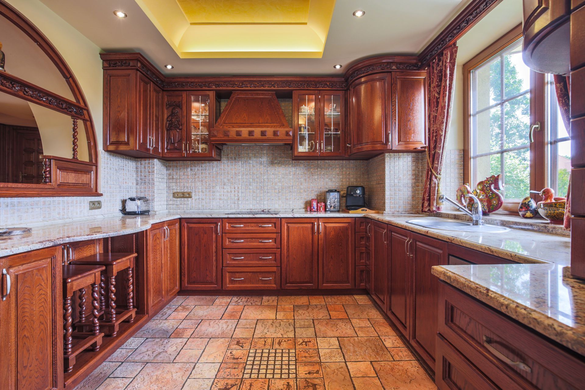 Spacious kitchen with dark wood cabinets, marble counters, tiled floor, and large windows by the sink