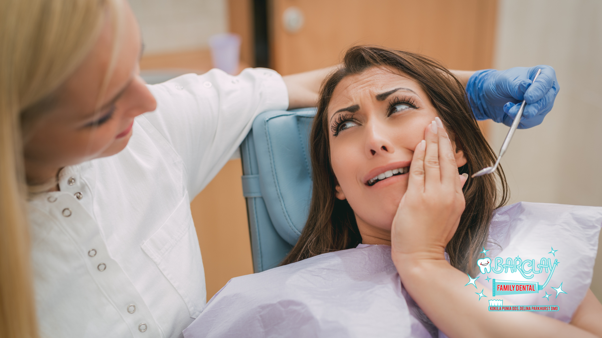 Woman with pained expression at the dentist, being examined with a dental pick.
