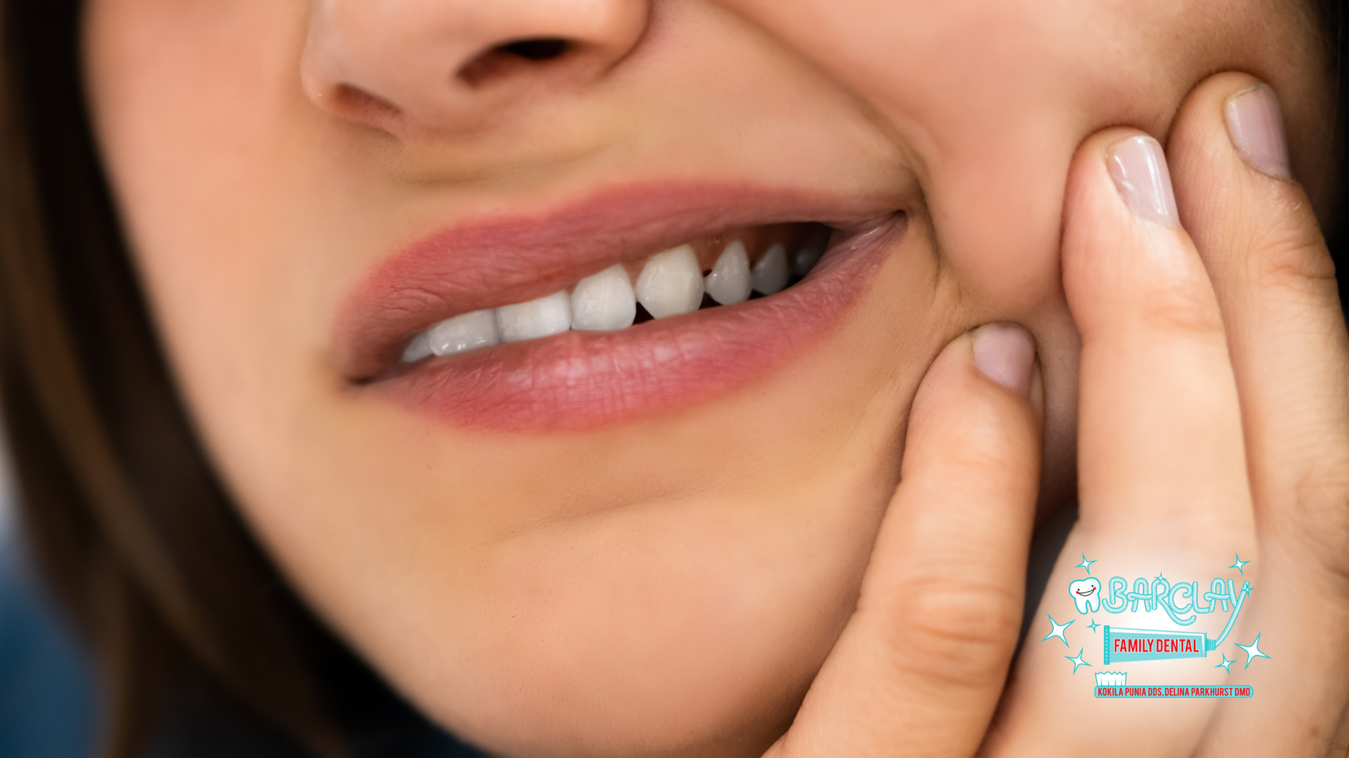 A woman is holding her mouth in pain because of a toothache.