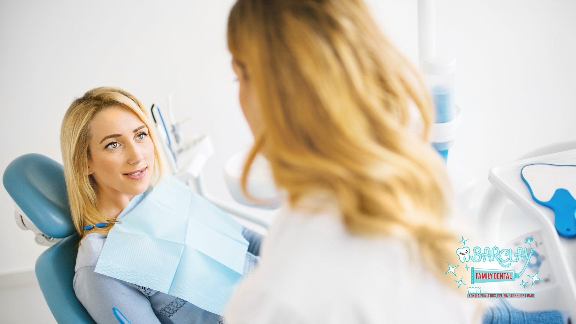 A woman is sitting in a dental chair talking to a dentist.