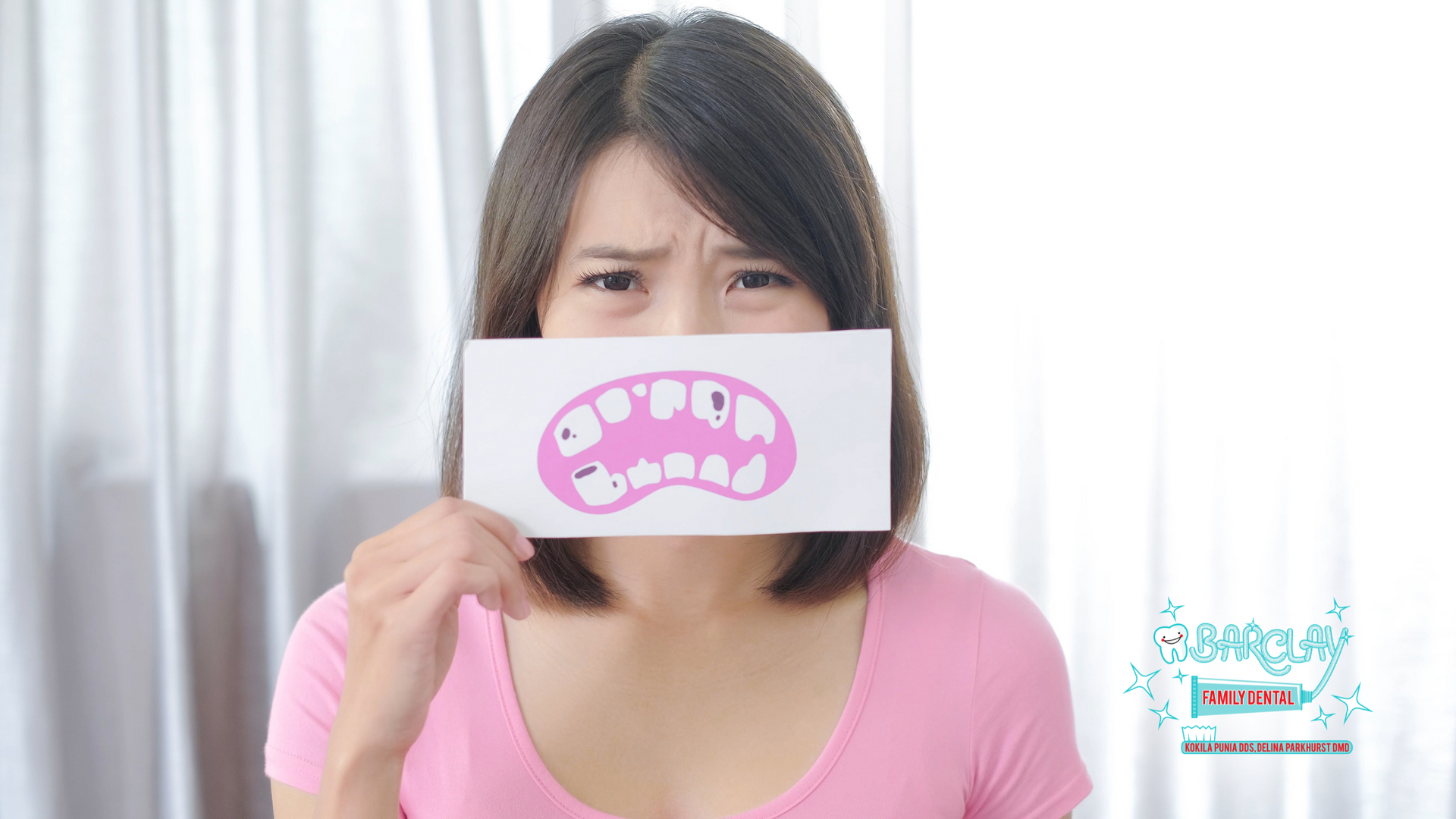 A woman is holding a piece of paper in front of her mouth.