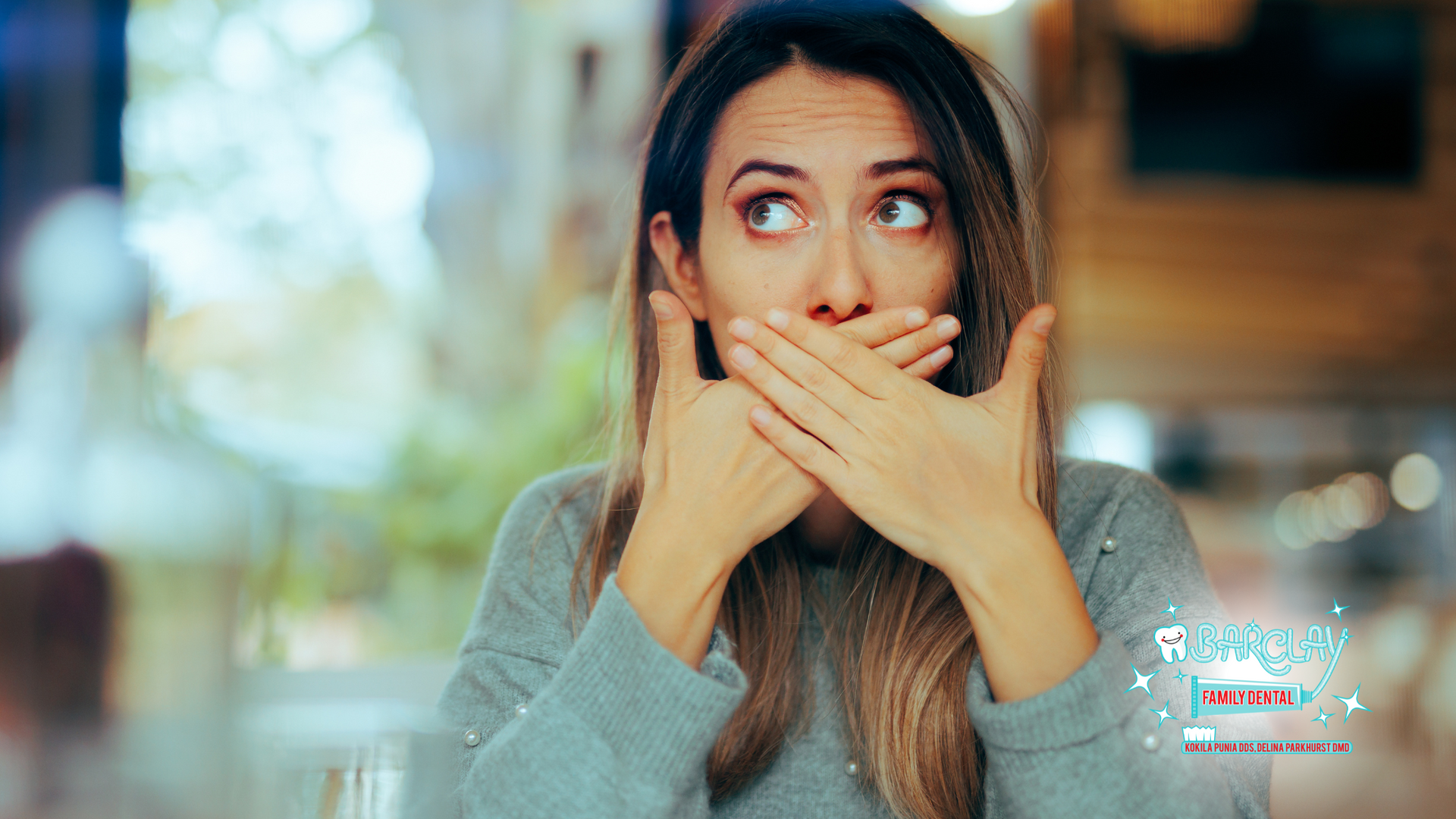 A woman is covering her mouth with her hands.