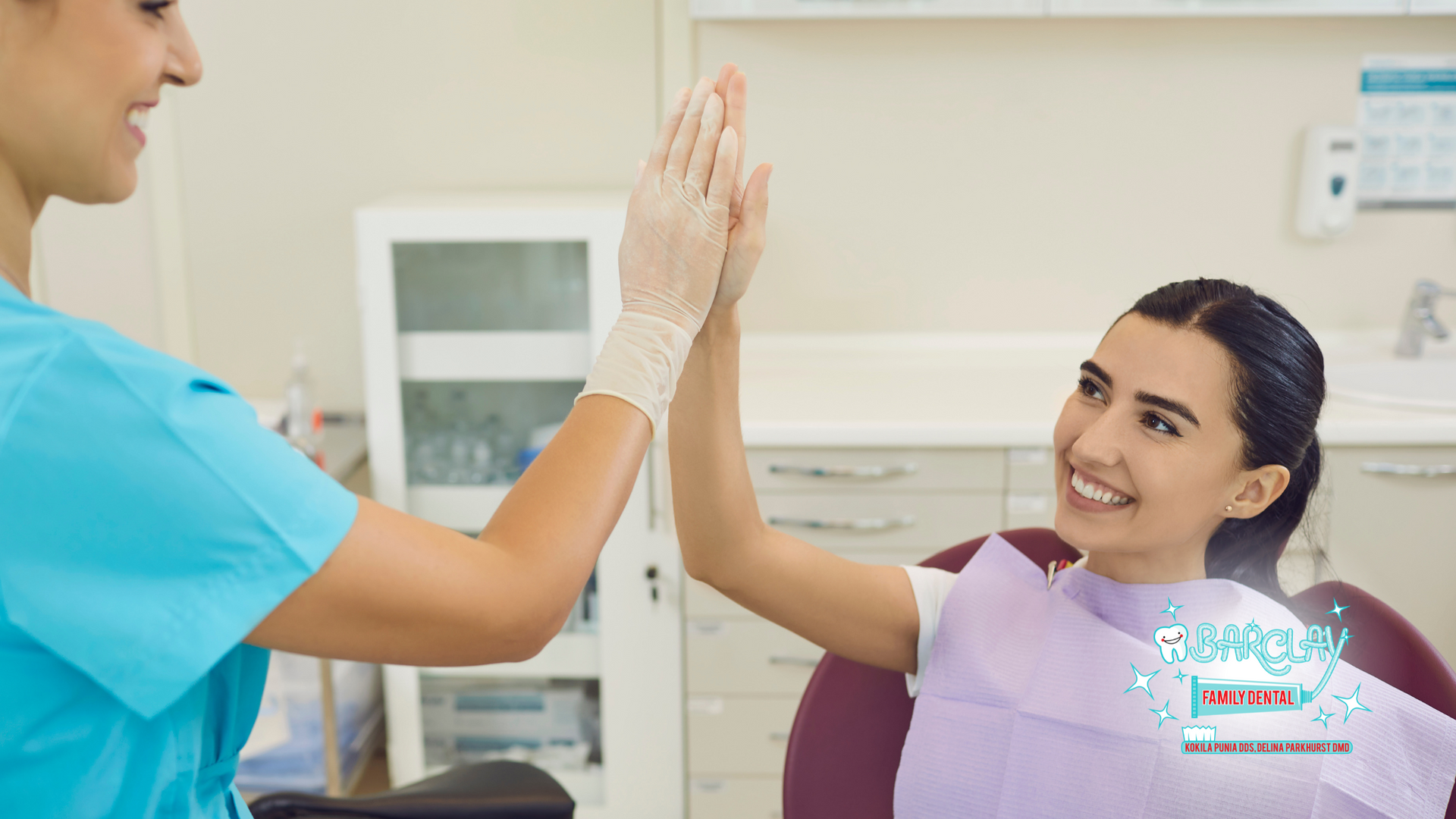Dentist and patient high-fiving in a dental office. Both smiling.