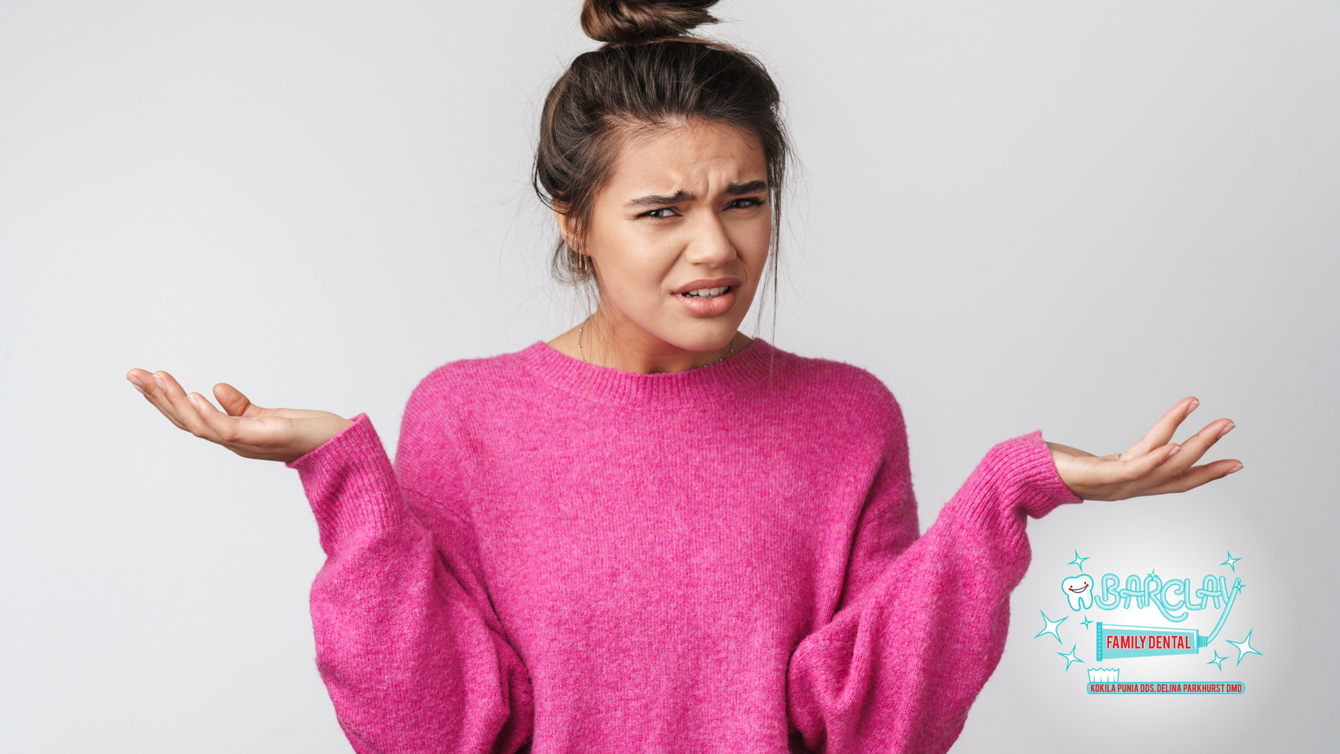 A woman in a pink sweater is shrugging her shoulders.