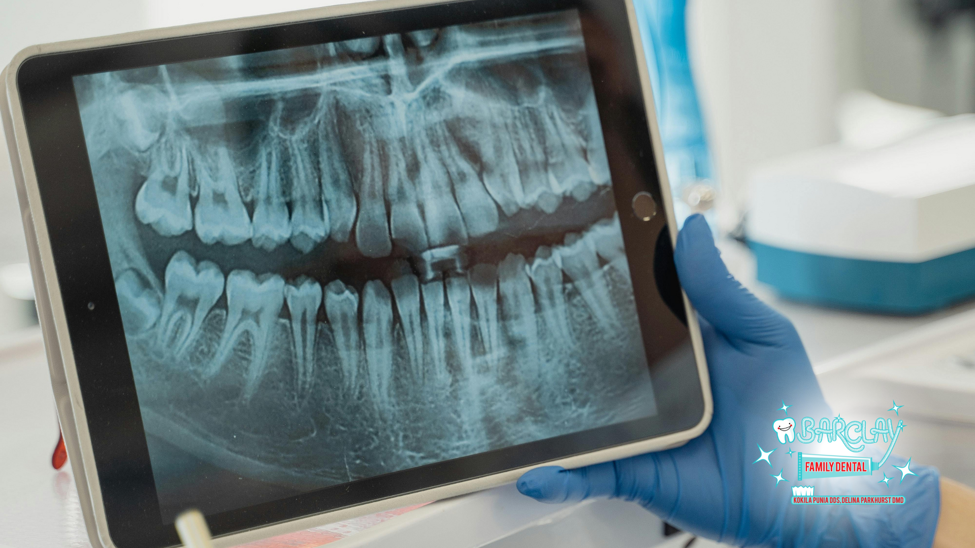 A dentist is holding a tablet with an x-ray of teeth on it.
