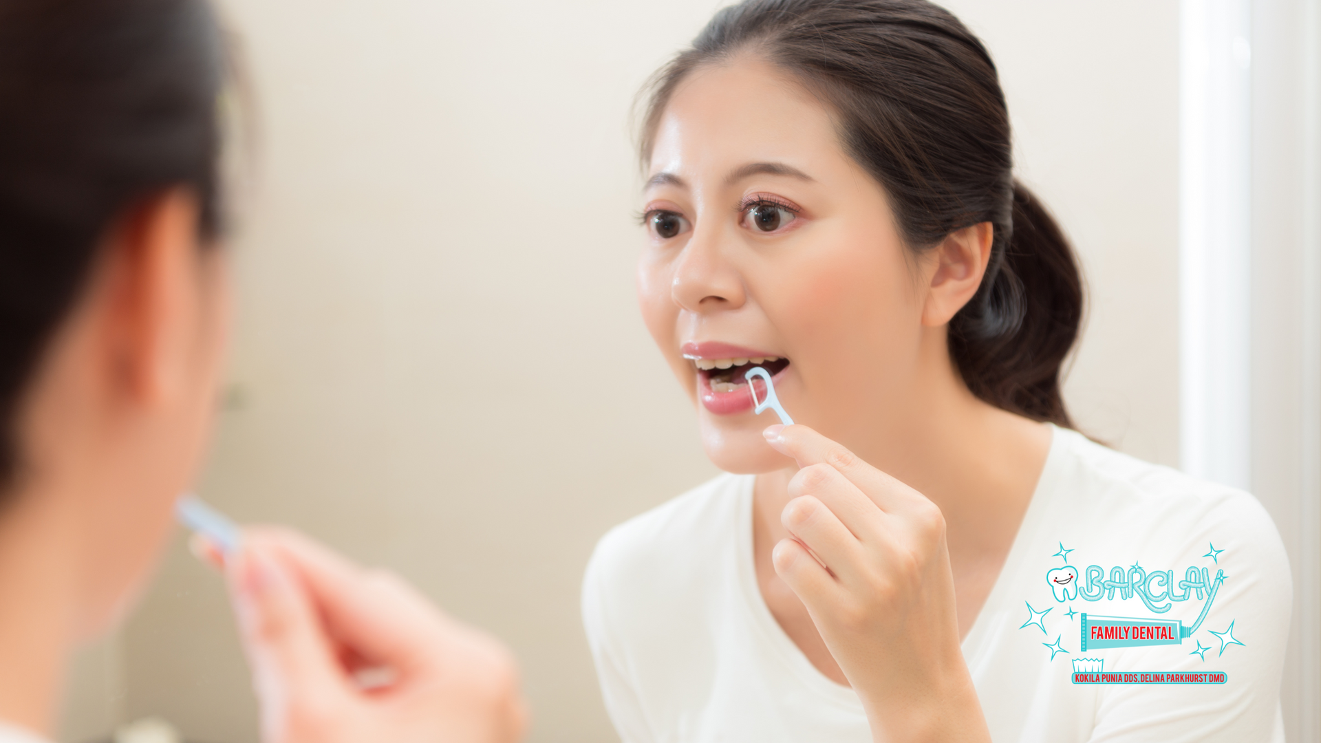 A woman is brushing her teeth in front of a mirror.