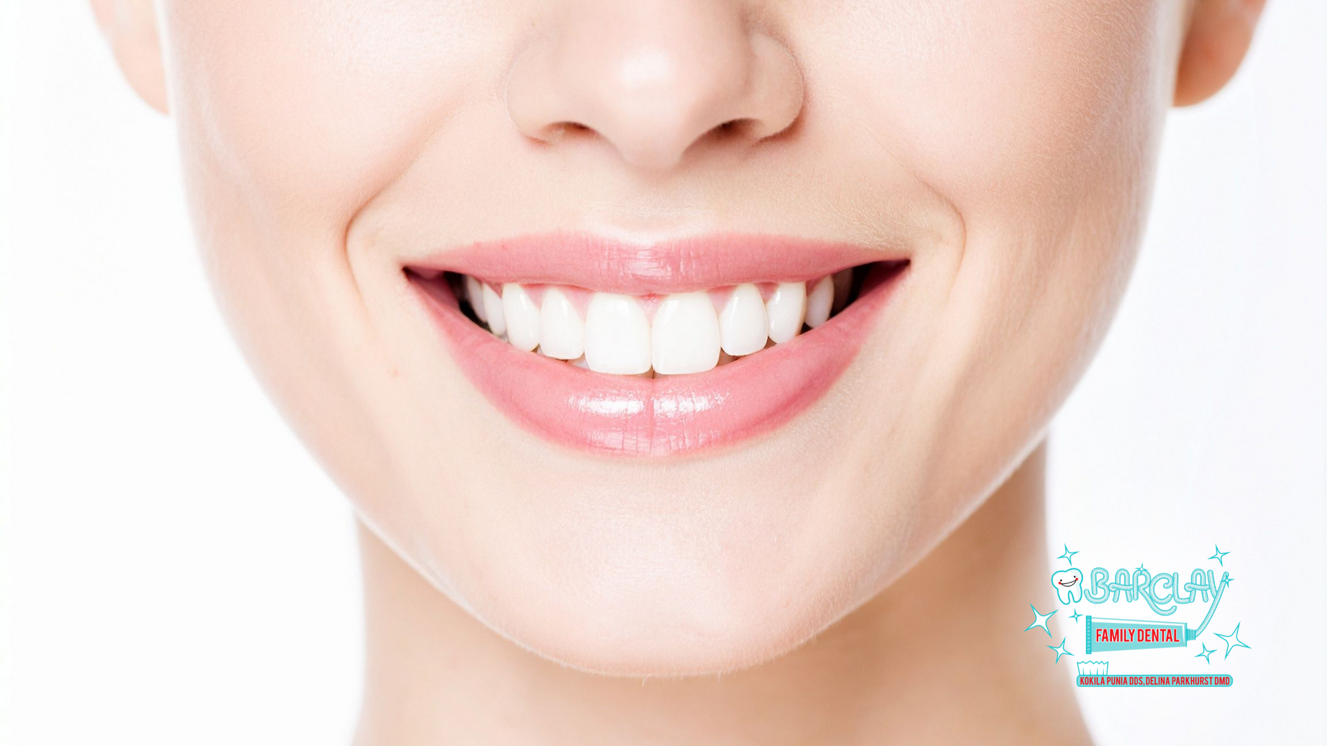 Close-up of a smiling woman with bright white teeth, pink lips, and a fair complexion.
