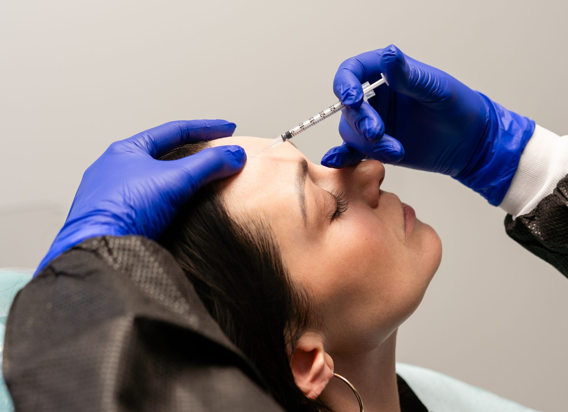 Woman receiving an injection in her neck, indoors, wearing a headband.