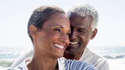 a man and a woman are hugging each other on the beach and smiling | Barclay Family Dental | Best Dentist For Family Dentistry, Dental Implants, and Cosmetic Dentistry in Cherry Hill, NJ