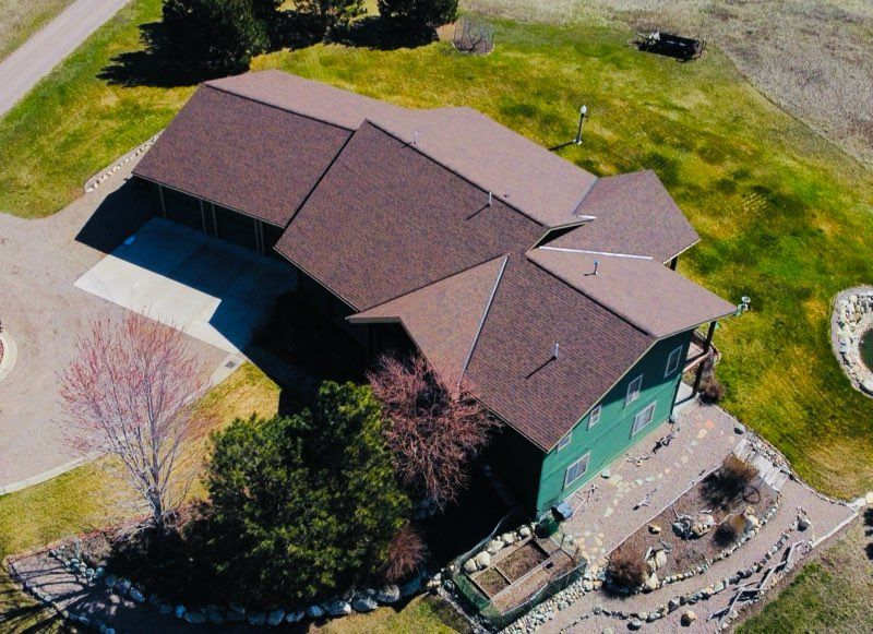 Steel frame construction of a building, with a telehandler and vehicles. People are present in a forested area.