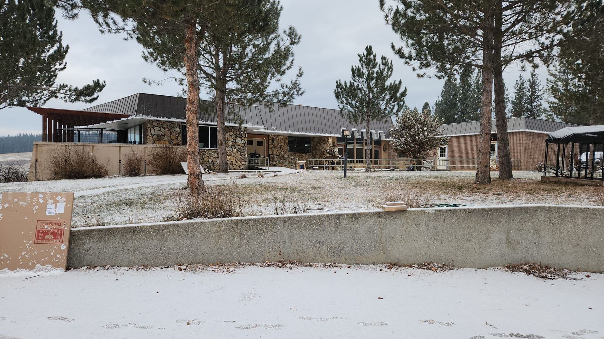 A large house is surrounded by snow and trees