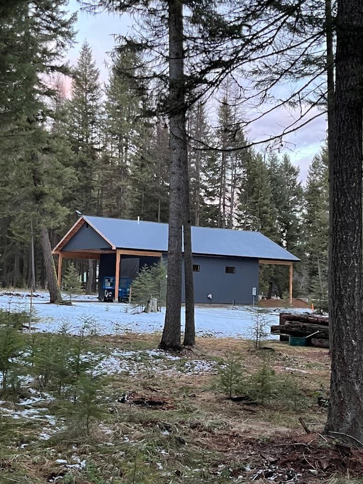 A house in the middle of a forest with snow on the ground