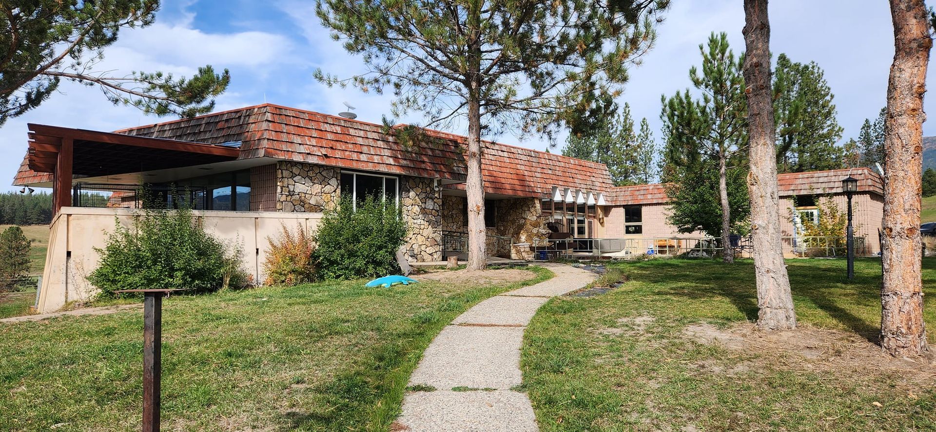 A house with a red tile roof is surrounded by trees and a path leading to it.