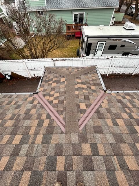 Rooftop deck with patterned shingles, pink trim, and a white fence overlooking neighboring houses.