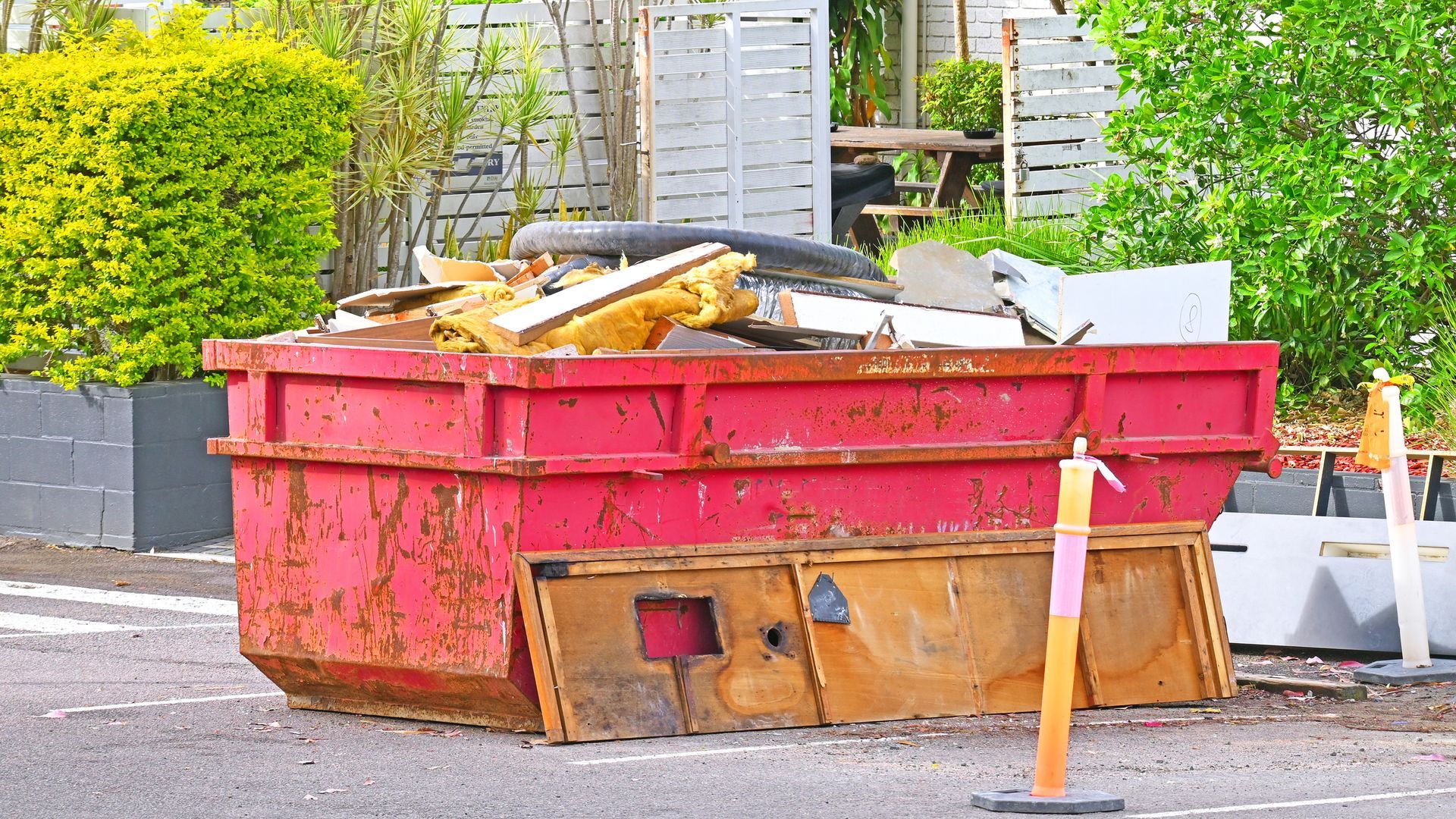 A garbage truck is driving down a street with garbage cans in front of it.