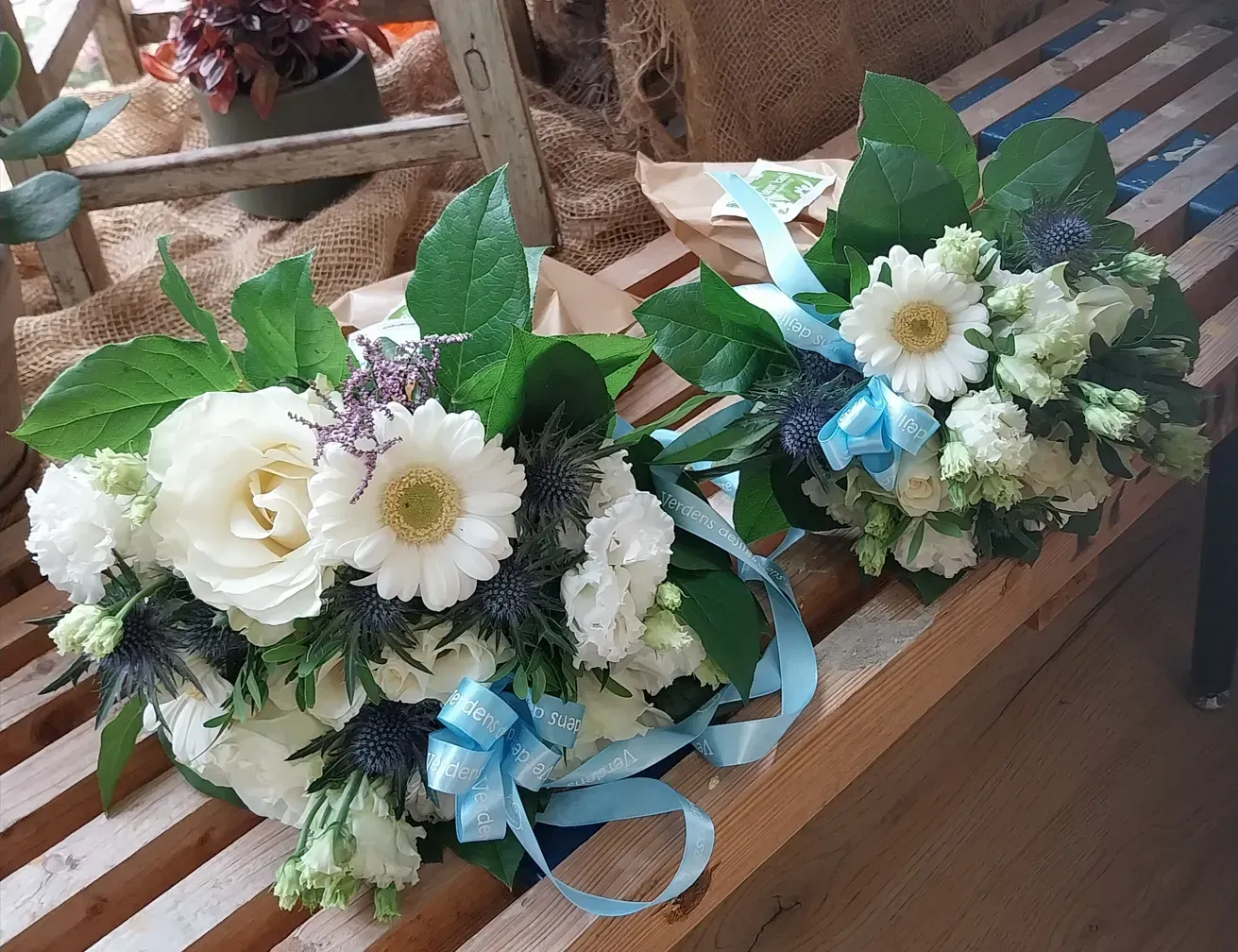 Mor-barn blomsterbuket med hvide blomster, grønt blad pynt og lyseblå silkebånd