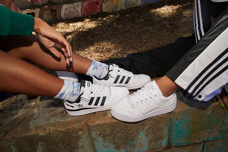 Zapatilla deportiva Adidas roja con rayas y suela blancas.