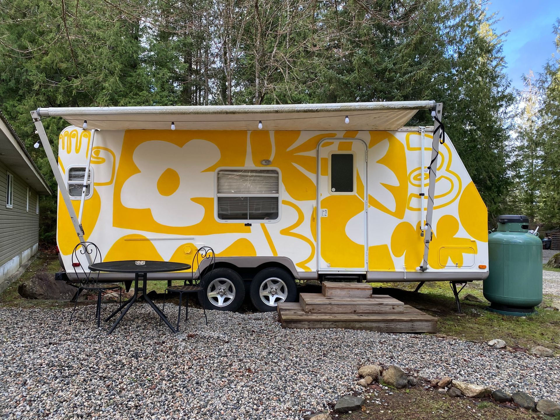 a group of people are sitting around a campfire in front of a trailer .