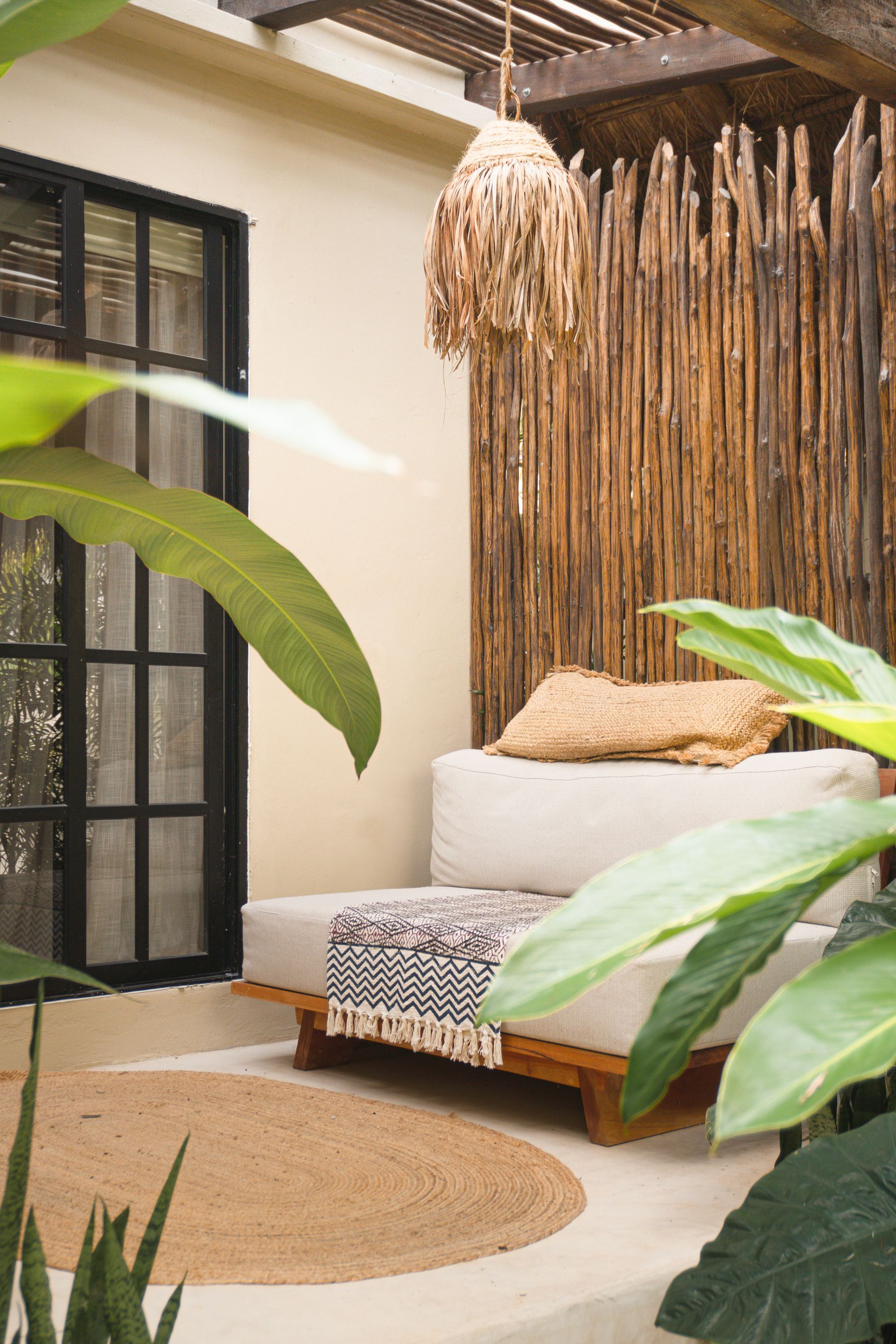 A wooden shelf with two vases and dried flowers against a white wall, near a window and curtain.