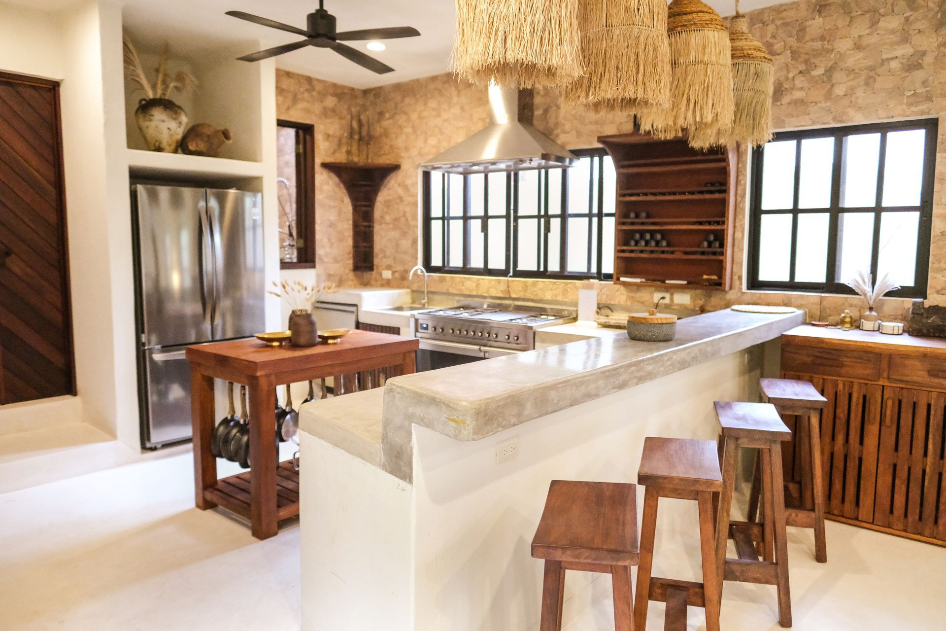 Kitchen with stone walls, stainless steel appliances, wooden cabinets, and a breakfast bar with stools.