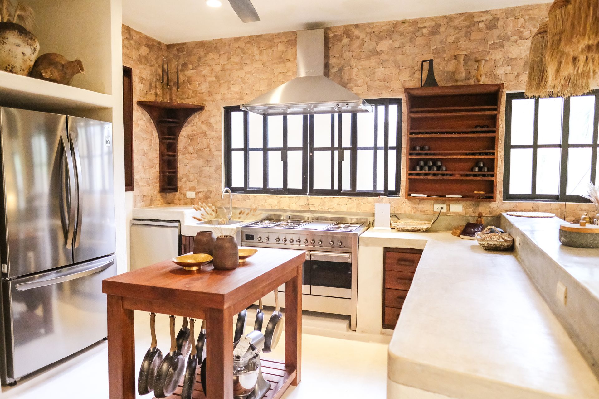 Rustic kitchen with stainless steel appliances, stone walls, and wooden island.
