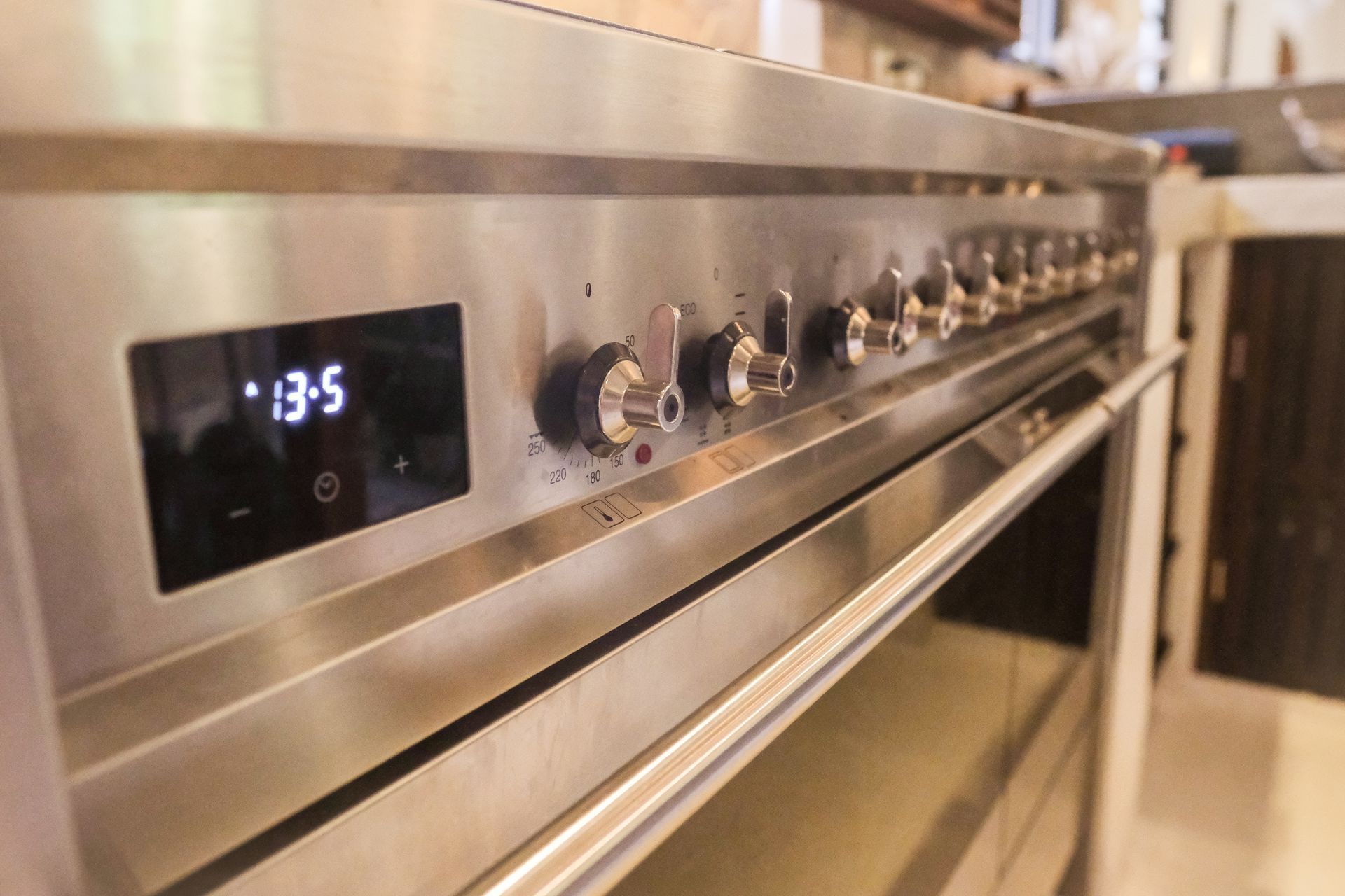 Stainless steel oven with digital display reading 13:5. Knobs line the stovetop.