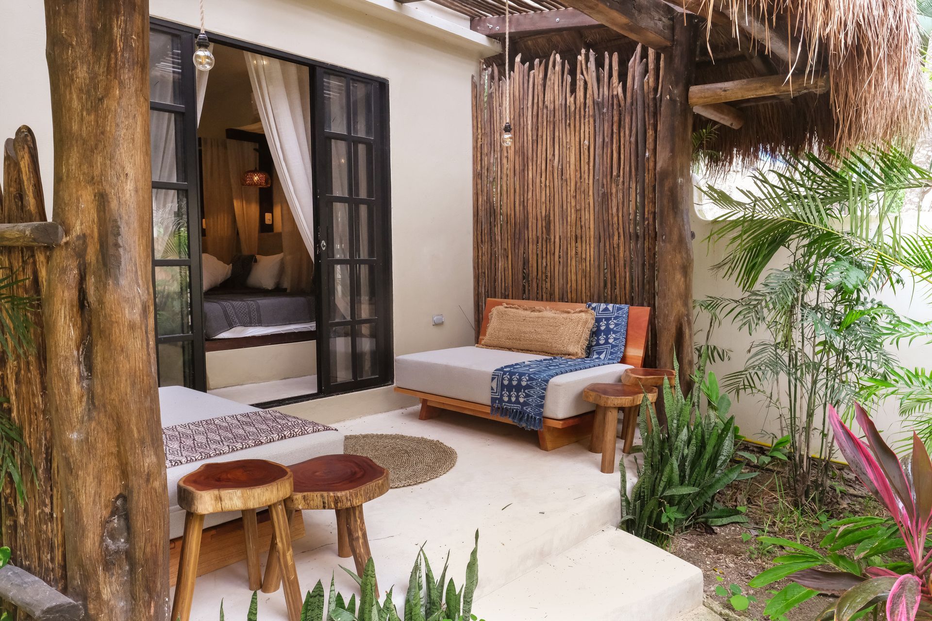 Outdoor patio with bed, seating, and wooden accents in a tropical setting.
