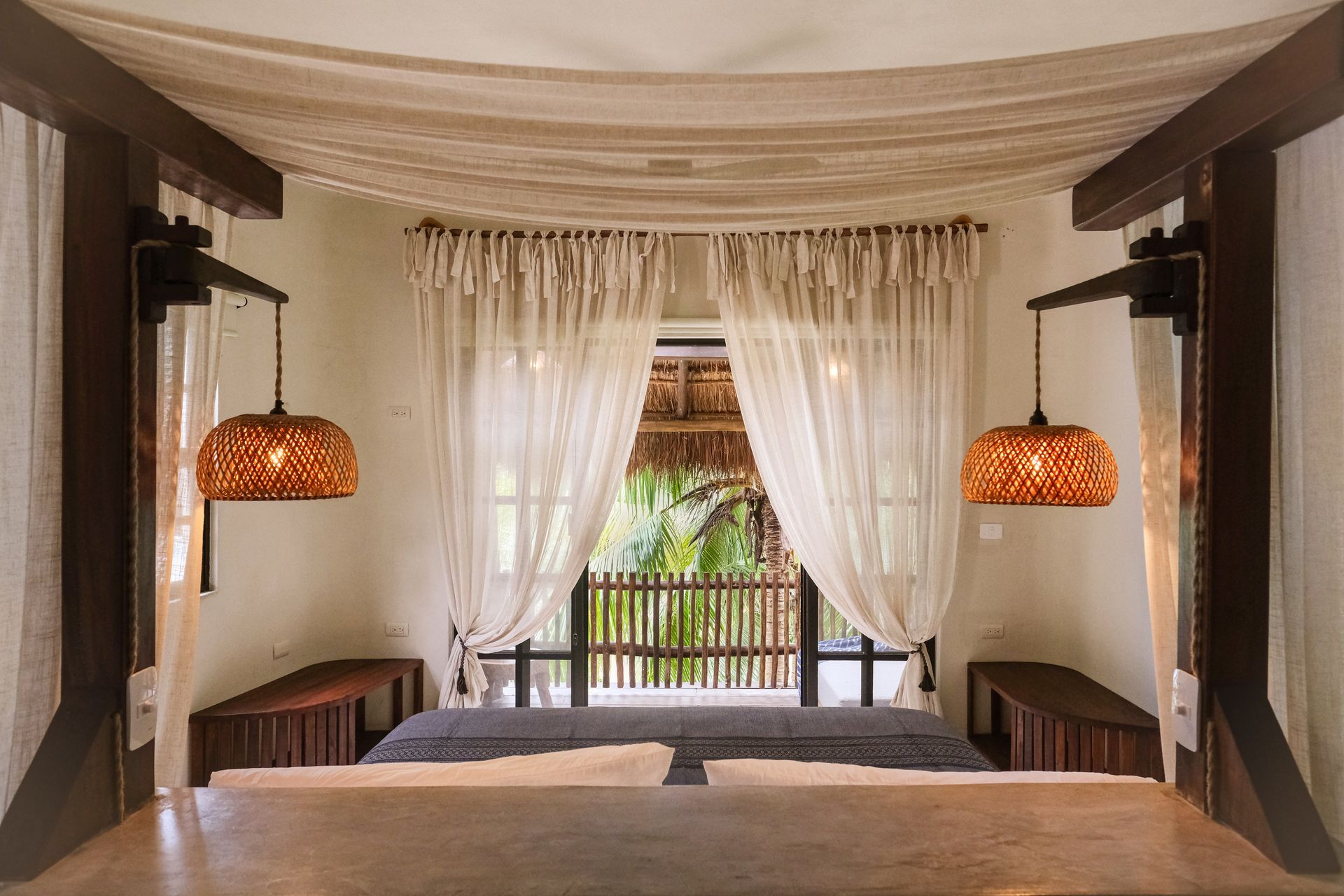 Bedroom with bed, open window, hanging lights, and neutral color scheme.
