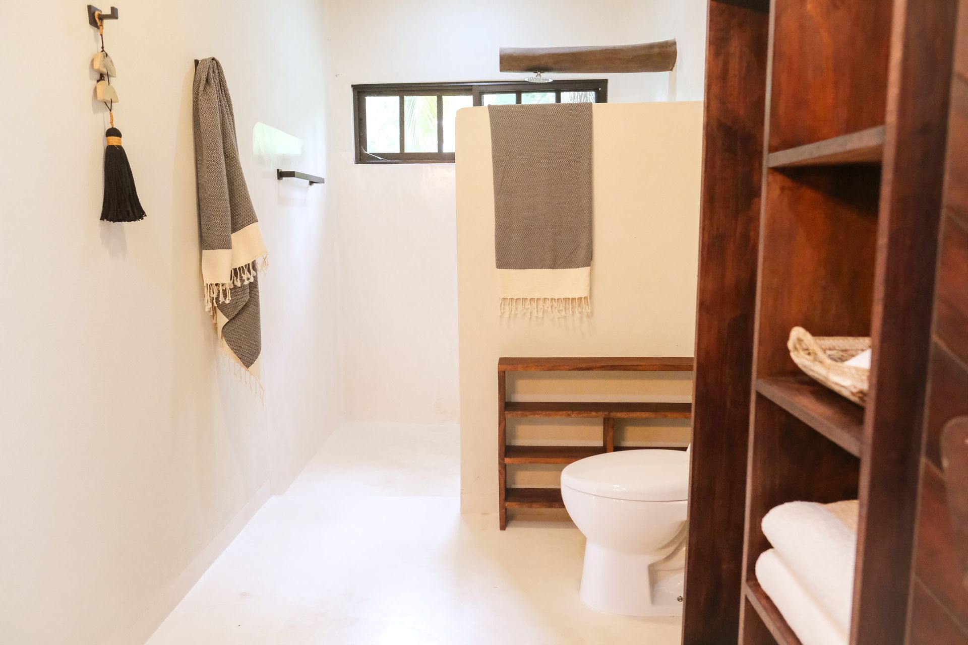 Bathroom with white walls, wooden shelves and accents, toilet, and towel rack.