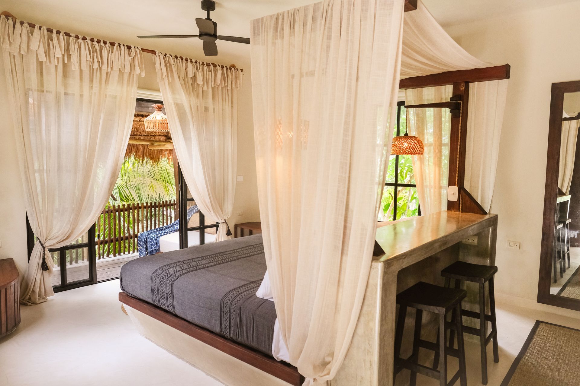 Bedroom with draped canopy bed, balcony access, and a bar with stools.