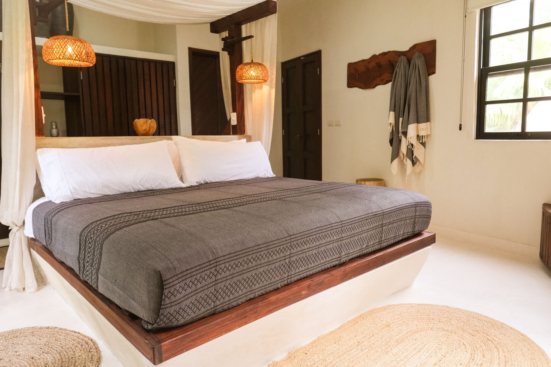 Bedroom with a canopy bed, wooden accents, and woven pendant lights.