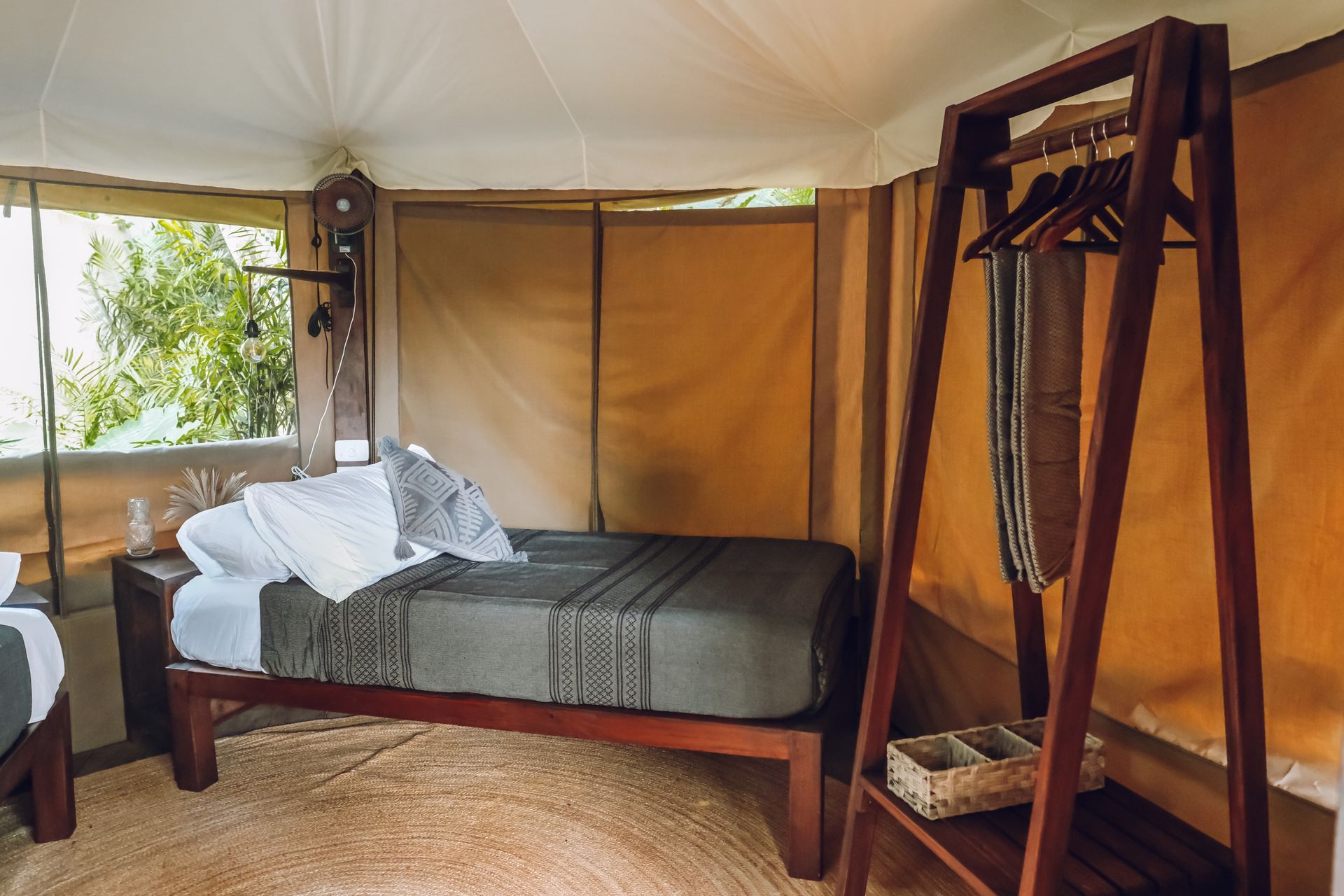 Interior of a glamping tent with bed, rug, and clothes rack.