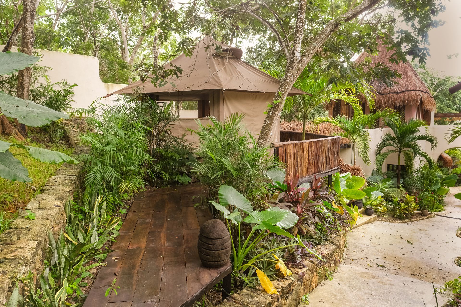 Wooden structure in lush tropical setting, with thatched roof building and walkway.