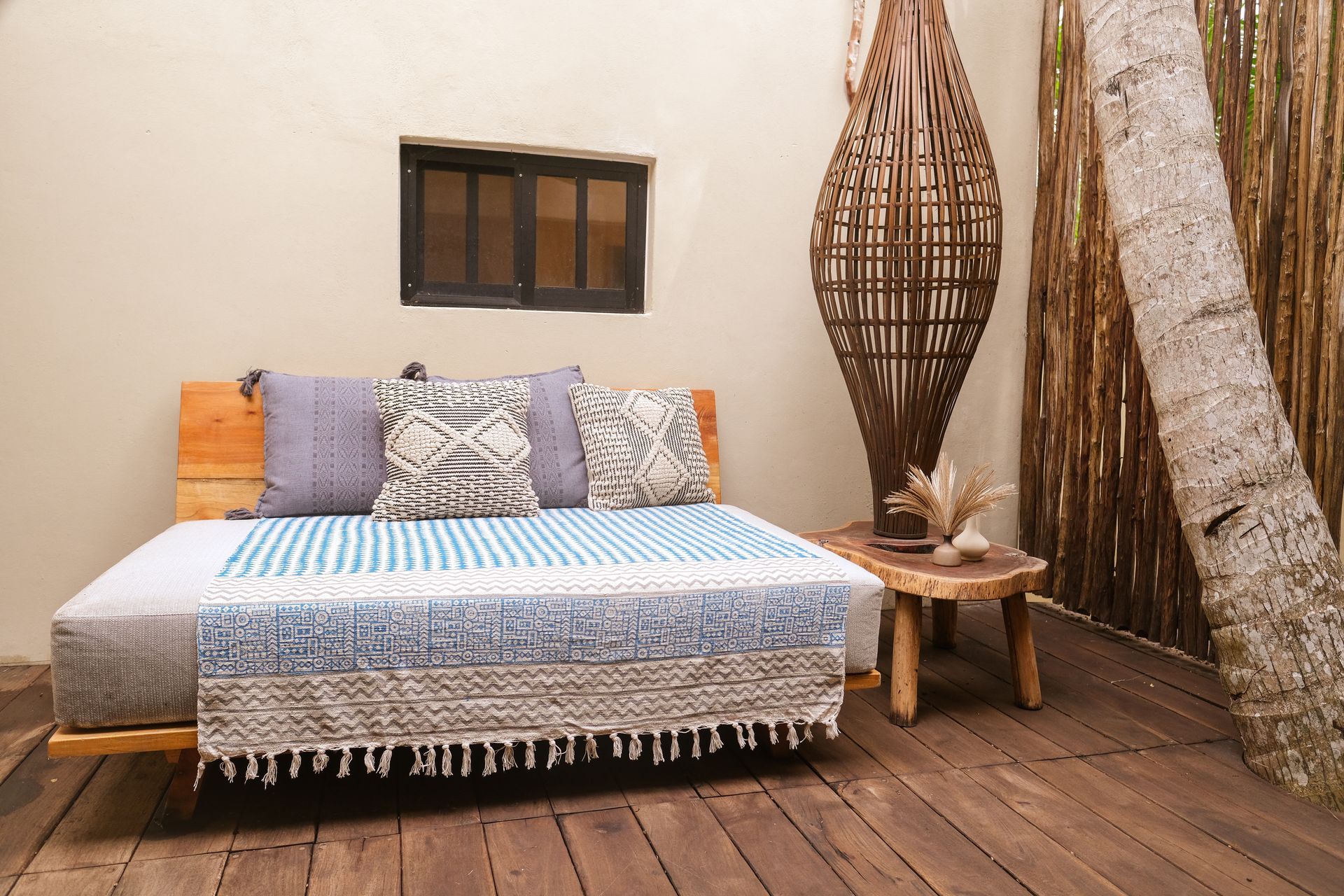 Outdoor daybed with blue and white blanket, pillows, and wooden accents.