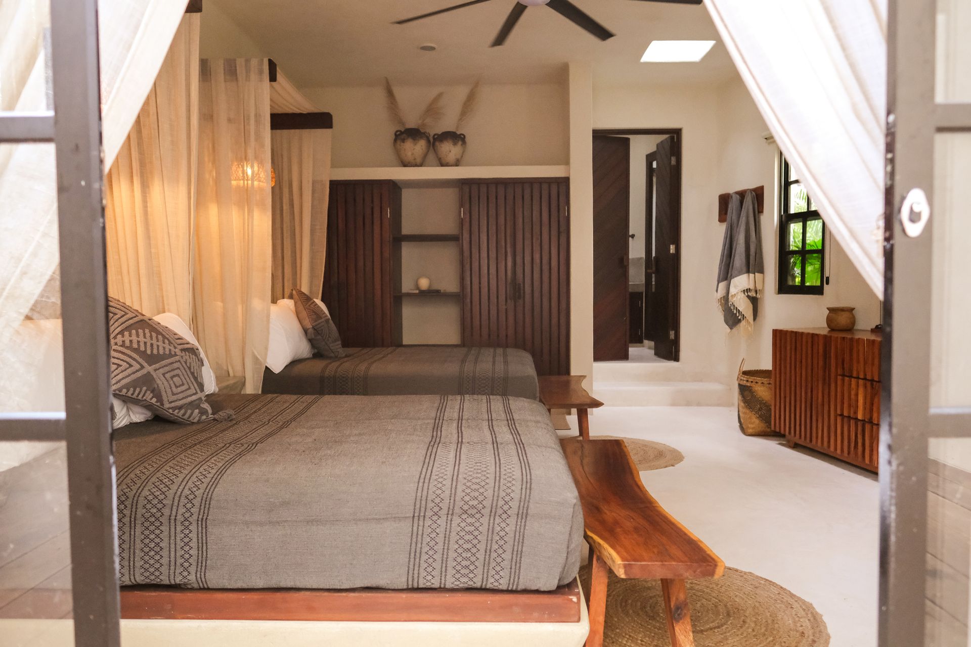Bedroom with two beds, wooden furniture, neutral color scheme, and open doorway to another room.