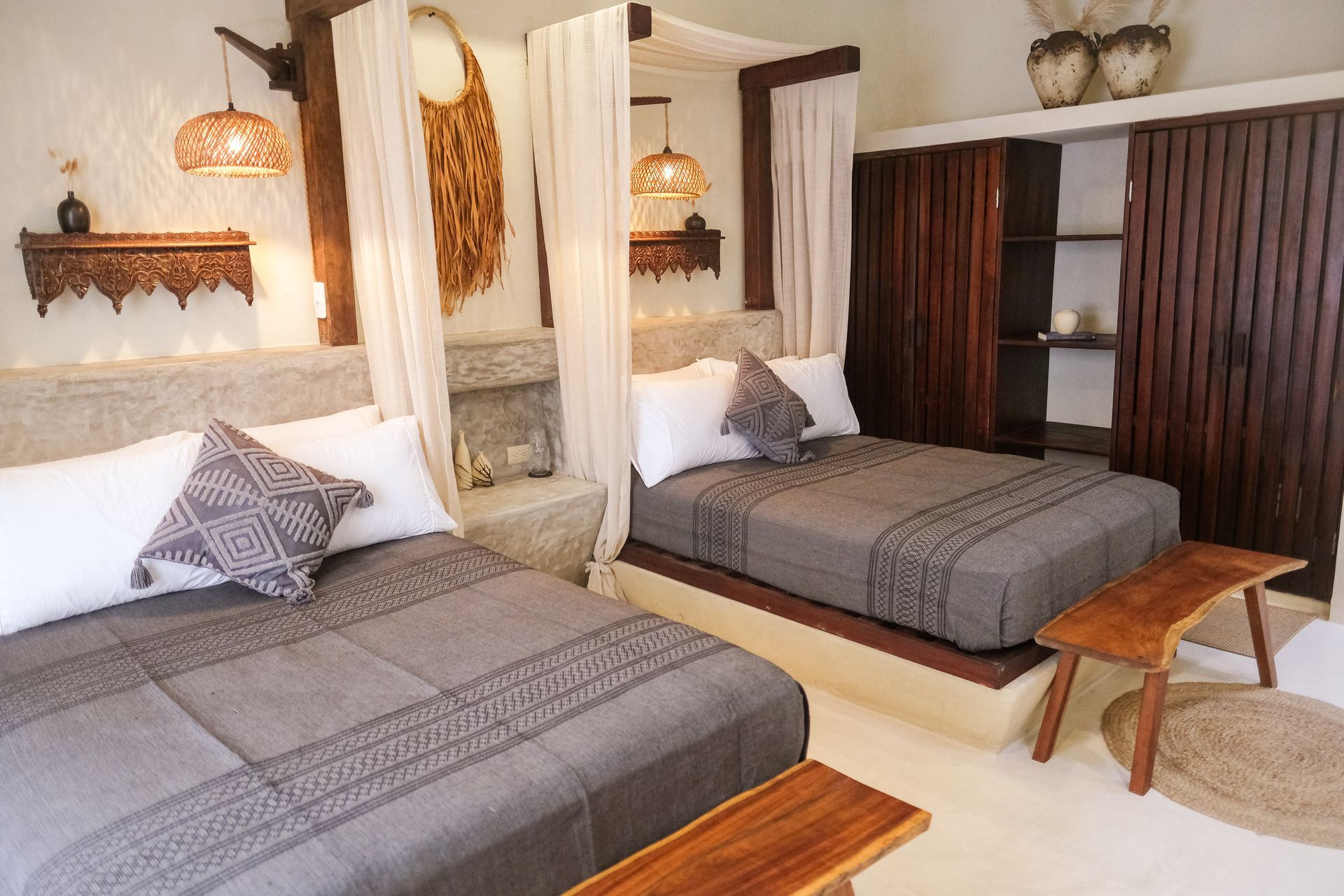 Two beds in a rustic bedroom with wooden accents, stone walls, and decorative hanging lamps.