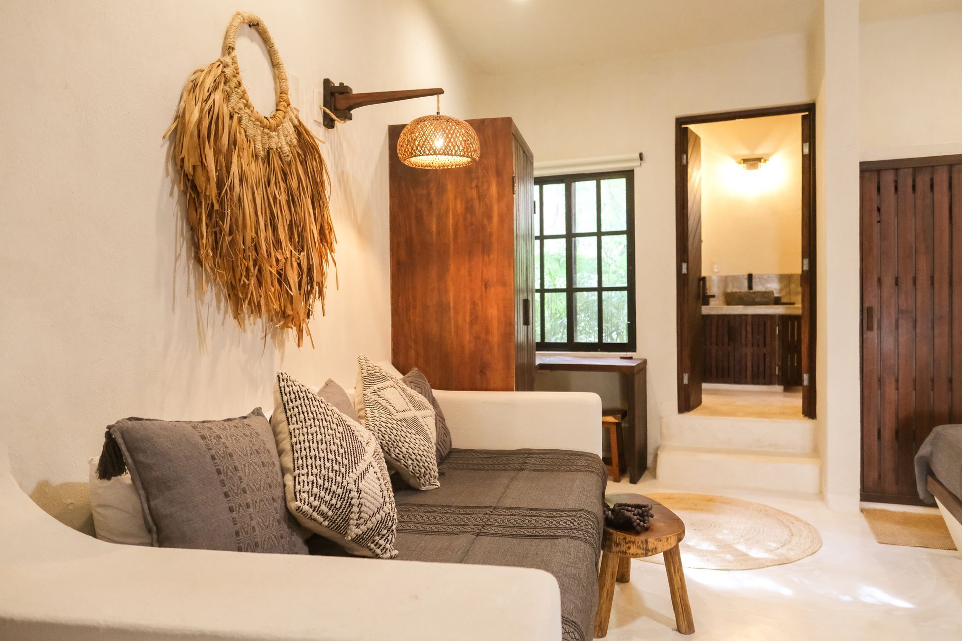 Living room with white walls, sofa, wooden furniture, and doorway to a bathroom.