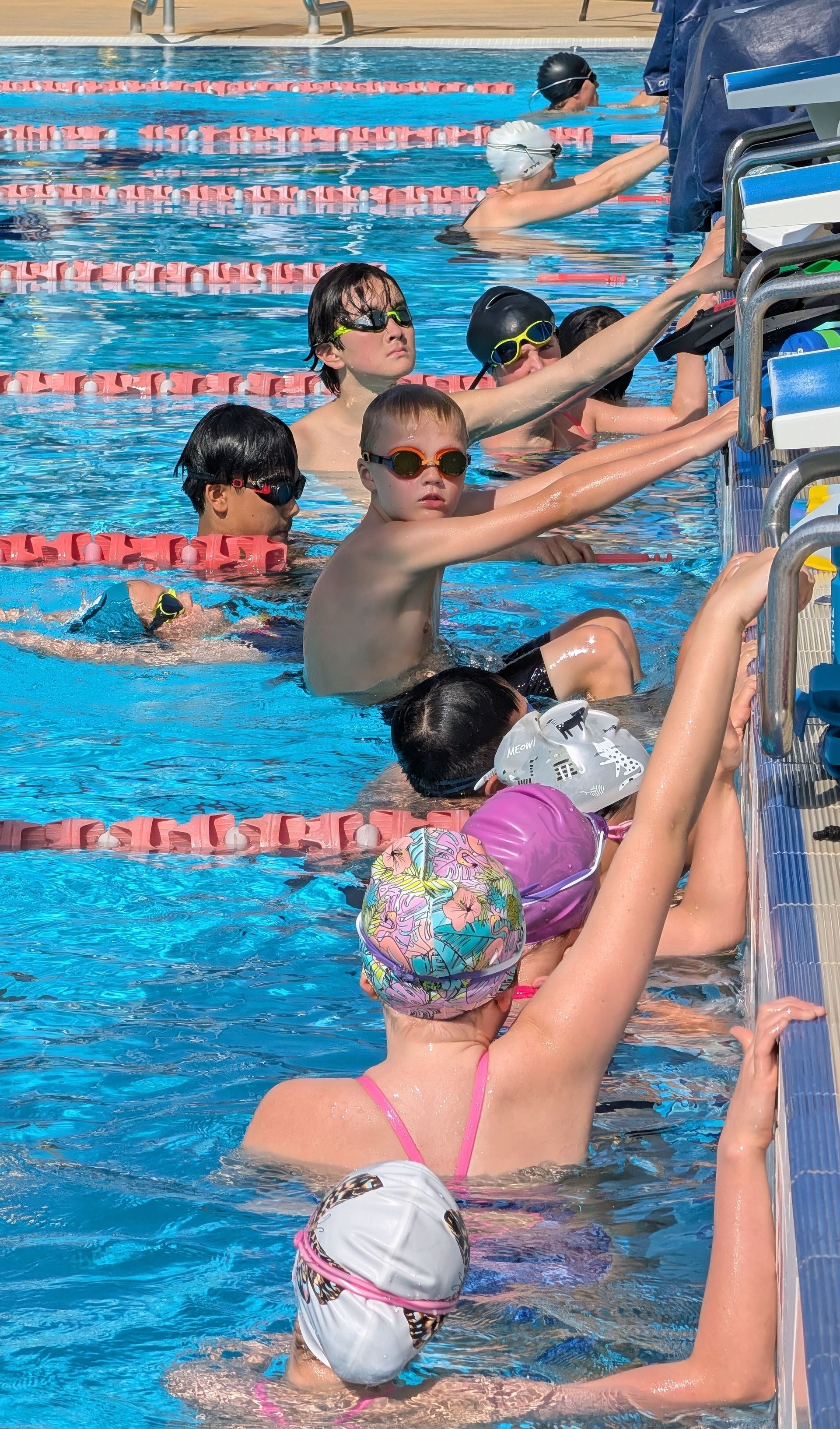 Female swimmer in red swimsuit, arching back in backstroke during a race in a pool.