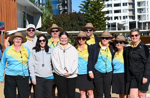 Group of people in hats and matching shirts, posing outdoors.